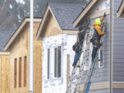Construction workers hold a piece of siding in place while building houses along Northeast 138th Avenue in east Vancouver.