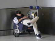 A traveler takes a nap as he waits for a ride outside Miami International Airport, Friday, July 1, 2022, in Miami. The Gallup survey, released Monday, April 15, 2024, says that a majority of Americans say they would feel better if they could have more sleep. But in the U.S., where the ethos of grinding and pulling yourself up by your own bootstraps is ubiquitous, getting enough sleep can seem like a dream.