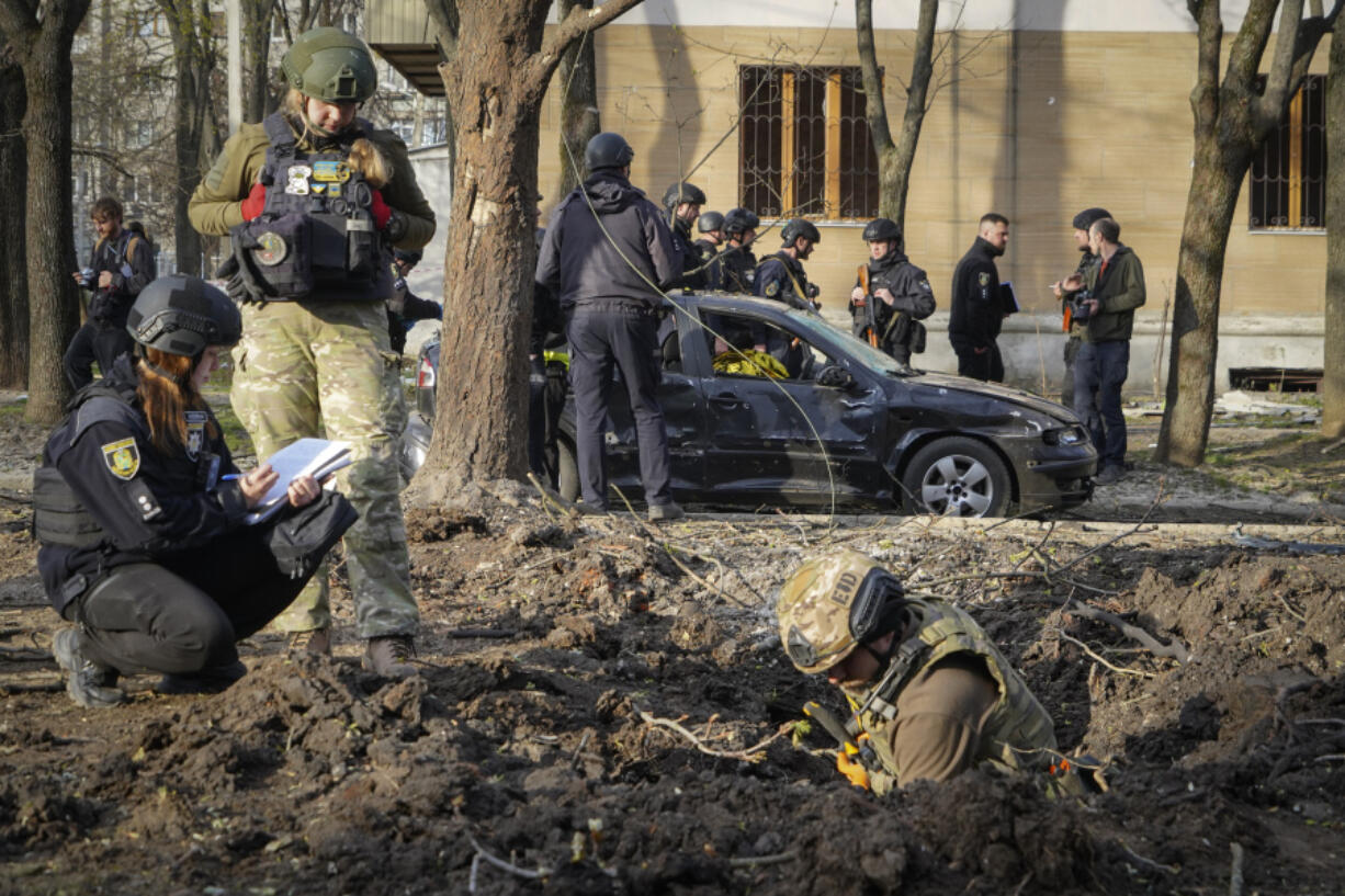 Military experts examine the site of a Russian bombing that killed several people in Kharkiv, Ukraine, Saturday, April 6, 2024.