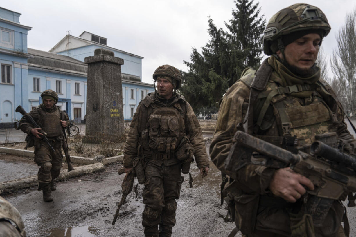 FILE - Ukrainian servicemen who recently returned from the trenches of Bakhmut walk on a street in Chasiv Yar, Ukraine, Wednesday, March 8, 2023. Approval by the U.S. House of a $61 billion package for Ukraine puts the country a step closer to getting an infusion of new firepower. But the clock is ticking. Russia is using all its might to achieve its most significant gains since the invasion by a May 9 deadline.