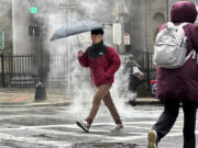 A pedestrian walks through downtown Boston during a rain storm, Wednesday, April 3, 2024. A nor&#039;easter has brought heavy wind, rain and snow to New England. (AP Photo/Robert F.