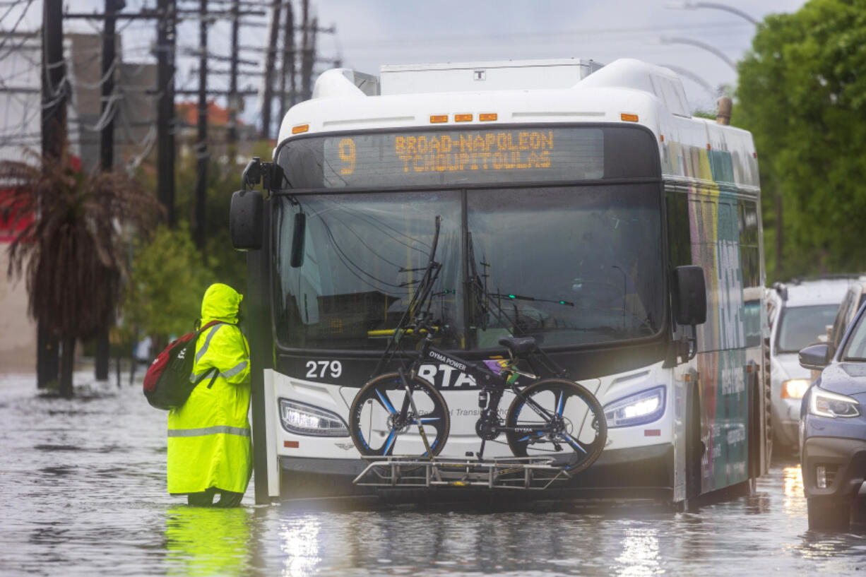 People stand in floodwaters as they try to get on a city bus during severe weather in New Orleans, on Wednesday, April 10, 2024.