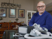 FILE - Jeffrey Reed, who experienced persistent sinus infections and two bouts of pneumonia while using a Philips CPAP machine, poses with the device at his home, Oct. 20, 2022, in Marysville, Ohio. The company responsible for a global recall of sleep apnea machines will be barred from resuming production at U.S. facilities until it meets a number of safety requirements under a long-awaited settlement announced Tuesday, April 9, 2024 by federal officials.