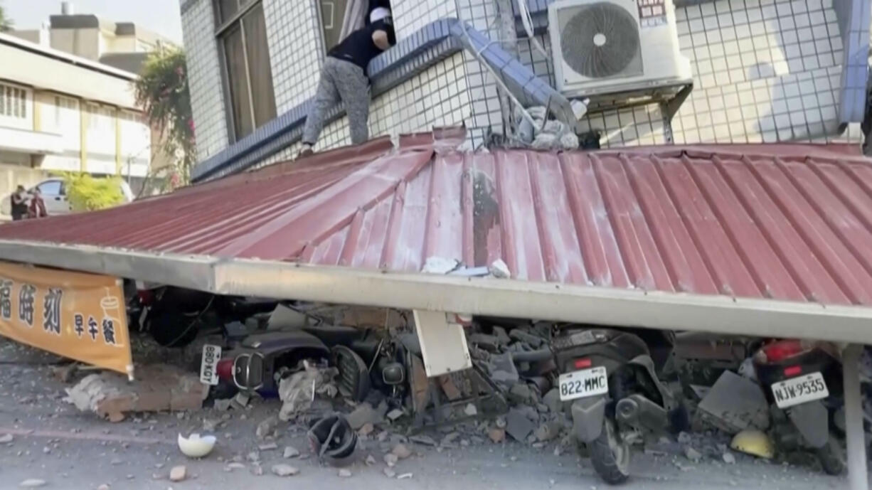 In this image taken from a video footage run by TVBS, a man checks a partially collapsed building in Hualien, eastern Taiwan on Wednesday, April 3, 2024.
