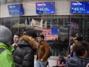 FILE - Pedestrians walk past the Nasdaq building Tuesday, March 26, 2024, in New York with the stock price of Trump Media &amp; Technology Group Corp., displayed on screens.