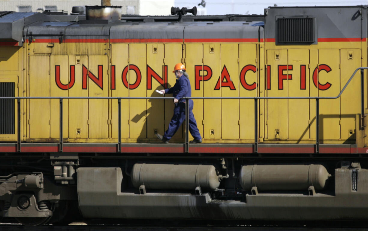 FILE - A maintenance worker walks past the company logo on the side of a locomotive in the Union Pacific Railroad fueling yard in north Denver, Oct. 18, 2006. Four railroads, including Union Pacific, have asked federal appeals courts to throw out a new rule that would require two-person train crews in most circumstances.