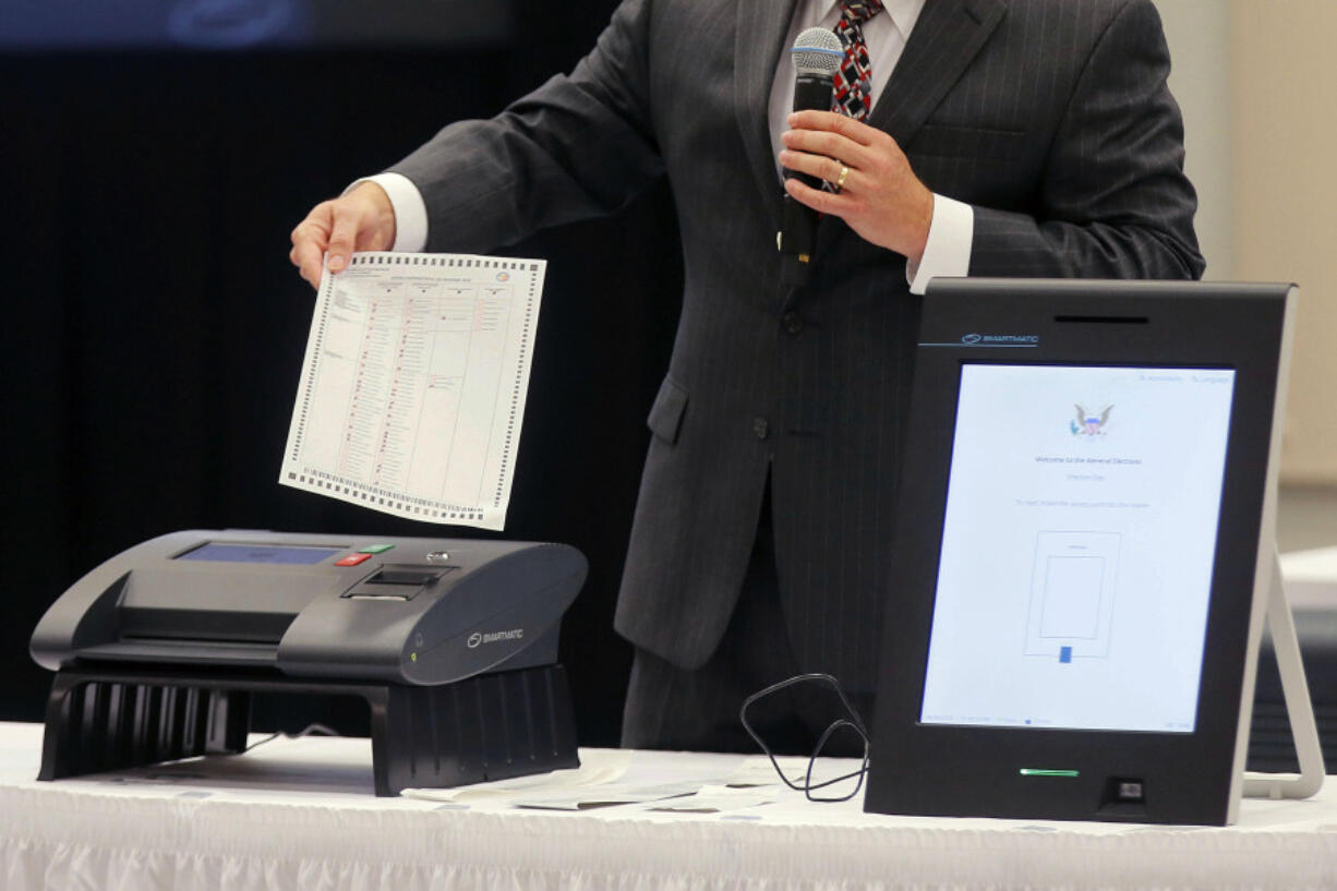 FILE - A Smartmatic representative demonstrates his company&rsquo;s system, which has scanners and touch screens with printout options, at a meeting of the Secure, Accessible &amp; Fair Elections Commission, Aug. 30, 2018, in Grovetown, Ga. The voting technology company targeted by bogus fraud claims related to the 2020 presidential election settled a defamation lawsuit Tuesday, April 16, 2024, against a conservative news outlet.