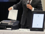 FILE - A Smartmatic representative demonstrates his company&rsquo;s system, which has scanners and touch screens with printout options, at a meeting of the Secure, Accessible &amp; Fair Elections Commission, Aug. 30, 2018, in Grovetown, Ga. The voting technology company targeted by bogus fraud claims related to the 2020 presidential election settled a defamation lawsuit Tuesday, April 16, 2024, against a conservative news outlet.