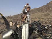 In this photo provided by Houthi media office Saturday, April, 27, 2024, a Houthi fighter celebrates in front of what they said debris of an American MQ9 aerial vehicle, shot down by the air defense forces of the Yemeni Armed Forces in Saada, Yemen, Friday, April, 26, 2024.