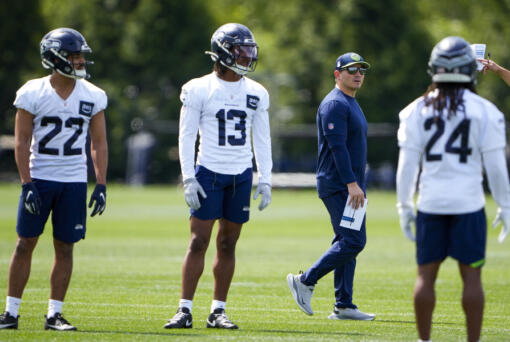 Seattle Seahawks head coach Mike Macdonald walks on the field past cornerback Andrew Hayes (22), strong safety JJ Ross (13) and free safety Irshaad Davis (24) during the NFL football team&#039;s rookie minicamp Friday, May 3, 2024, in Renton, Wash.