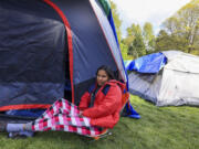 Genesis Perez, 31, who is from Venezuela and is seeking U.S. asylum, waits Tuesday by a tent that she and her family slept in overnight without access to shelter at Powell Barnett Park in Seattle.