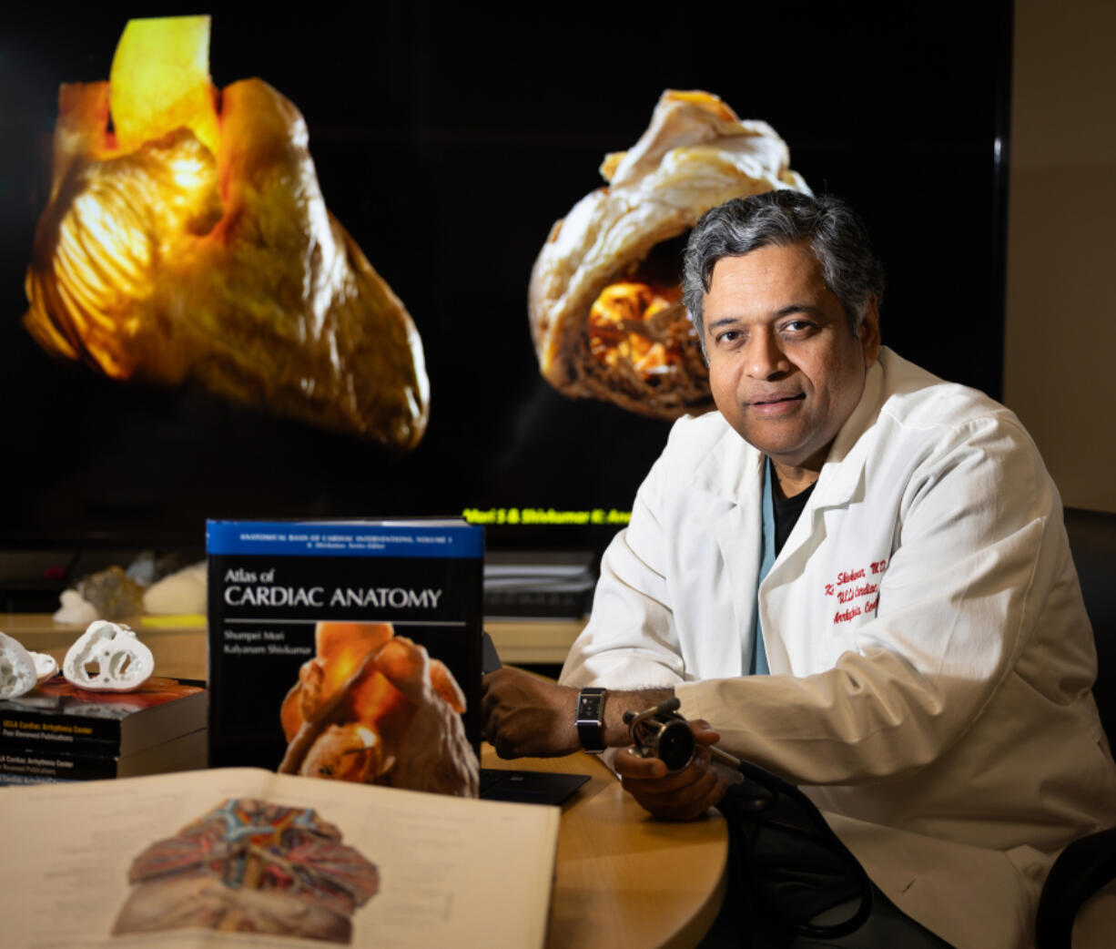 Dr. Kalyanam Shivkumar, professor of medicine with the UCLA Cardiac Arrhythmia Center, shown with his book book titled &ldquo;Atlas of Cardiac Anatomy&rdquo; and a book by Dr. Eduard Pernkopf, an ardent Nazi whose anatomical book was drawn off the bodies of executed prisoners, shown in foreground, May 9, 2024. (Allen J.