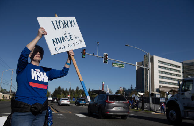 Registered nurse Jennifer Anderson greets morning traffic while picketing outside PeaceHealth Southwest Medical Center on Thursday morning, April 18, 2024.