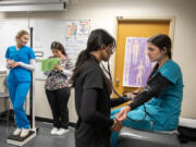 From left: Cascadia Tech Academy student Hannah Freimuth, 18, has her height and weight measured by classmate Leslie Vega, 17, as Unzila Alauddin, 17, takes the blood pressure of fellow student Mia Yanez, 18, on Friday afternoon. The medical assisting program at Cascadia Tech Academy allows students to gain clinical experience at local clinics and hospitals.
