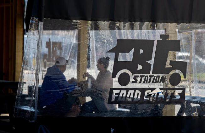 Arthur Colunga of Battle Ground, left, and his wife, Lyndsey, grab a bite to eat Thursday while enjoying the outdoor seating area at the new Battle Ground Station food cart pod on Main Street. At top, a customer picks up an order from Bobablastic in Battle Ground on Thursday morning.