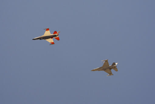 An AI-enabled Air Force F-16 fighter jet, left, flies next to an adversary F-16, as both aircraft race within 1,000 feet of each other, trying to force their opponent into vulnerable positions, on Thursday, May 2, 2024, above Edwards Air Force Base, Calif. The flight is serving as a public statement of confidence in the future role of AI in air combat. The military is planning to use the technology to operate an unmanned fleet of 1,000 aircraft.