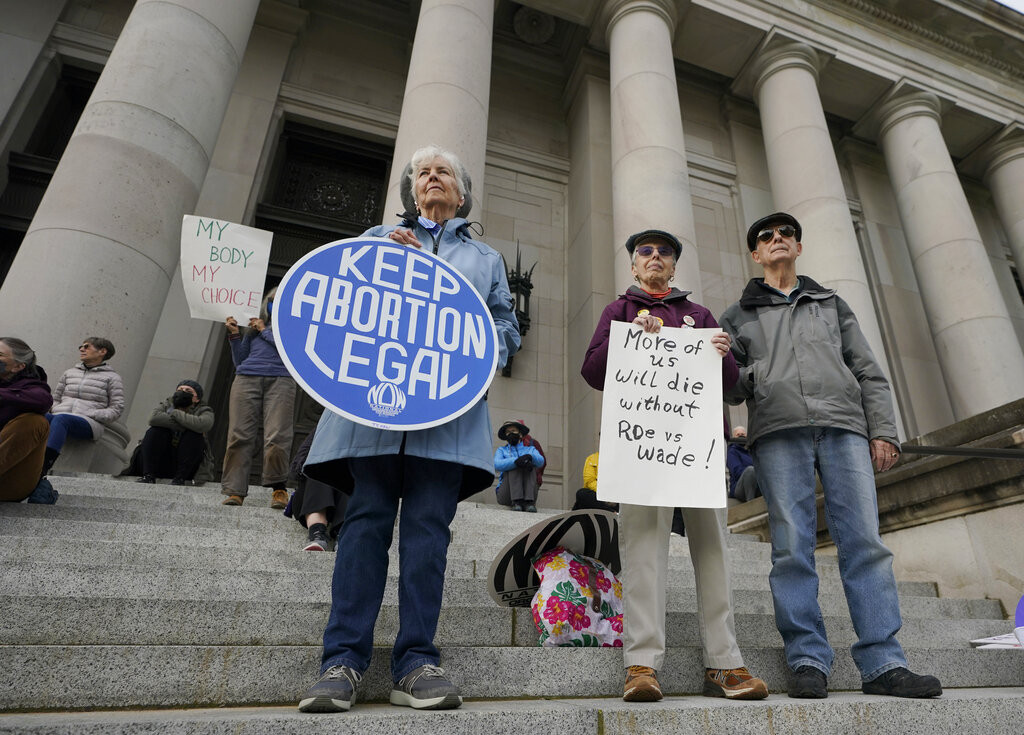 People hold signs in favor of abortion rights as they stand on the steps of the Temple of Justice, which houses the Washington state Supreme Court, during an evening rally, Tuesday, May 3, 2022, at the Capitol in Olympia, Wash. (AP Photo/Ted S.