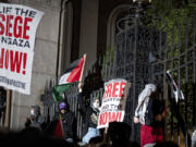 Pro-Palestianian protesters gather near a main gate at Columbia University in New York, Tuesday, April 30, 2024, just before New York City police officers cleared the area after a building was taken over by protesters earlier in the day. The building and a tent encampment were cleared during the operation.