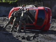 Ukrainian servicemen turn over a damaged car at the scene of a Russian missile attack in Zaporizhzhia, Ukraine, Wednesday, May 8, 2024.