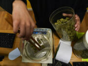 Budtender Rey Cruz weighs cannabis for a customer at the Marijuana Paradise on Friday, April 19, 2024, in Portland, Ore.