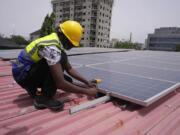 Oladapo Adekunle, an engineer with Rensource Energy, installs solar panels on a roof of a house in Lagos, Nigeria, Thursday, March 21, 2024. Funding for climate tech startups in Africa from the private sector is growing, but there&rsquo;s still a long way to go.