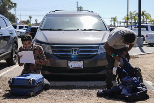 Migrants check their baggage at a parking lot after being detained and processed for asylum by U.S authorities Tuesday, May 7, 2024, in San Diego.
