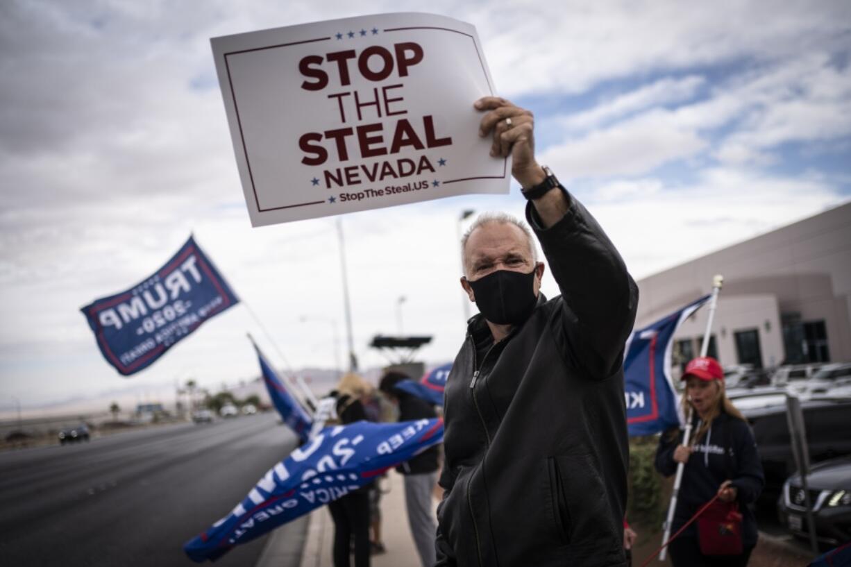 FILE - Supporters of President Donald Trump hold signs as they stand outside of the Clark County Elections Department in North Las Vegas,Nov. 7, 2020.