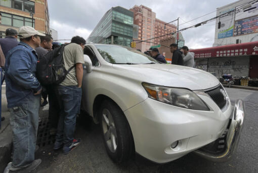Wang Gang, 36, center left, a Chinese immigrant, talks with the driver of a car with others as they try to get a daily paid job working construction or in another trade in the Flushing neighborhood of the Queens borough of New York on May 3, 2024. The daily struggle to find work for Chinese immigrants living illegally in Flushing is a far cry from the picture Donald Trump and other Republicans have sought to paint about them. Asian advocacy organizations say they&rsquo;re concerned the exaggerated rhetoric could fuel further harassment against Asians in the U.S.