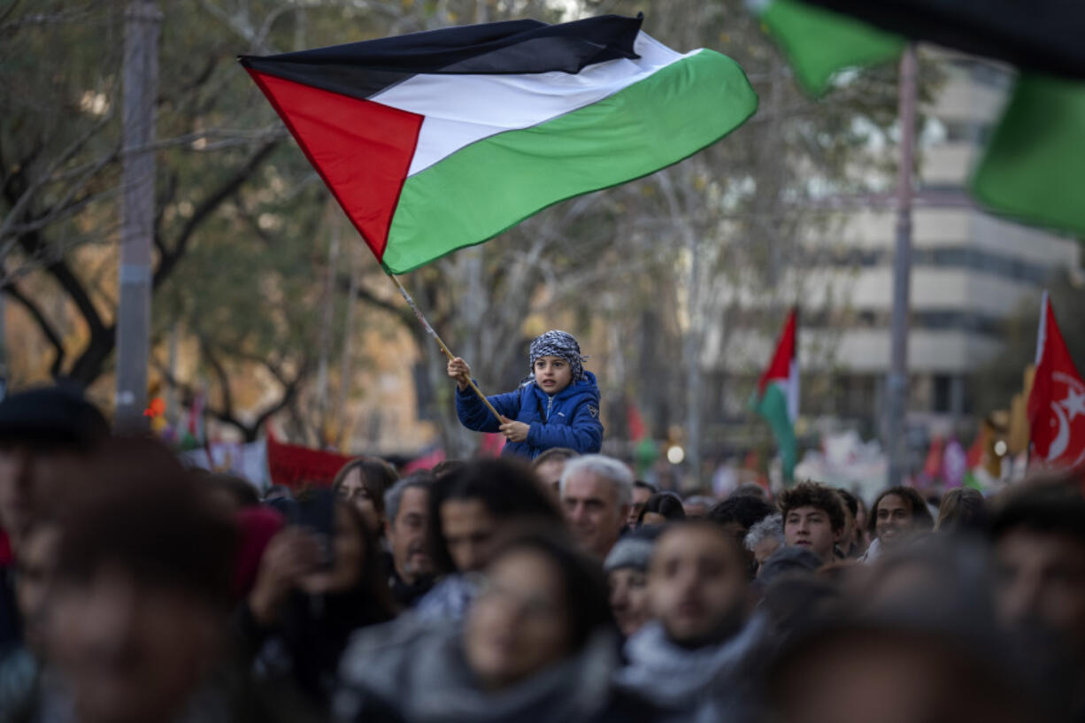 FILE - A boy waves a Palestinian flag as demonstrators march during a protest in support of Palestinians and calling for an immediate ceasefire in Gaza, in Barcelona, Spain, on Jan. 20, 2024. European Union countries Spain and Ireland as well as Norway on Wednesday announced dates for recognizing Palestine as a state.