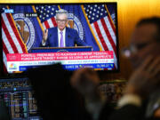 A screen displays a news conference with Federal Reserve Chairman Jerome Powell as traders work on the floor at the New York Stock Exchange in New York, Wednesday, May 1, 2024.