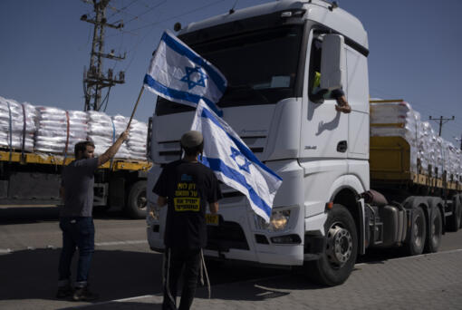 Holding Israeli flags people stand in front of trucks carrying humanitarian aid as they try to stop them to enter in the Gaza Strip in an area near the Kerem Shalom border crossing between Israel and Gaza, in southern Israel, in Kerem Shalom, Thursday, May 9, 2024.