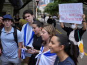 A Pro-Palestinian protester holds up a sign as Jewish students talk to the media following on campus at the University of Texas at Austin, Tuesday, April 30, 2024, in Austin, Texas.
