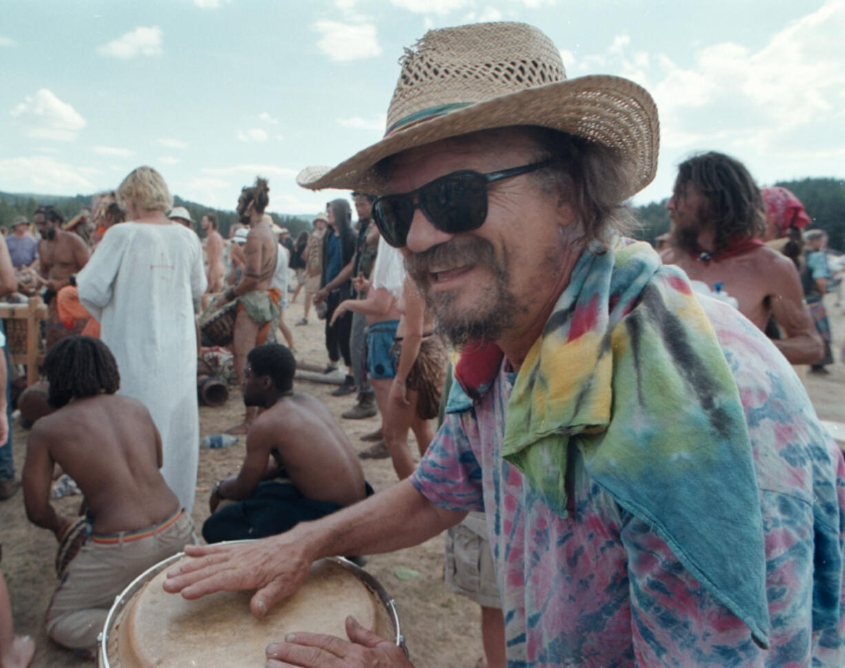 A man plays drums while others dance July 4, 2001, during The Rainbow Family Gathering in Cache Creek Meadow, Idaho.