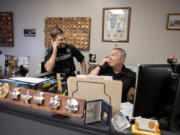 Deputy Bryson Layton, left, of the Clark County Sheriff's Office jokingly talks on his radio as he mimics his dad, Deputy DuWayne Layton, taking a call at his desk June 3 in downtown Vancouver. DuWayne Layton said his son was like his shadow when the 22-year-old was a boy, and they now work together at the sheriff&rsquo;s office.