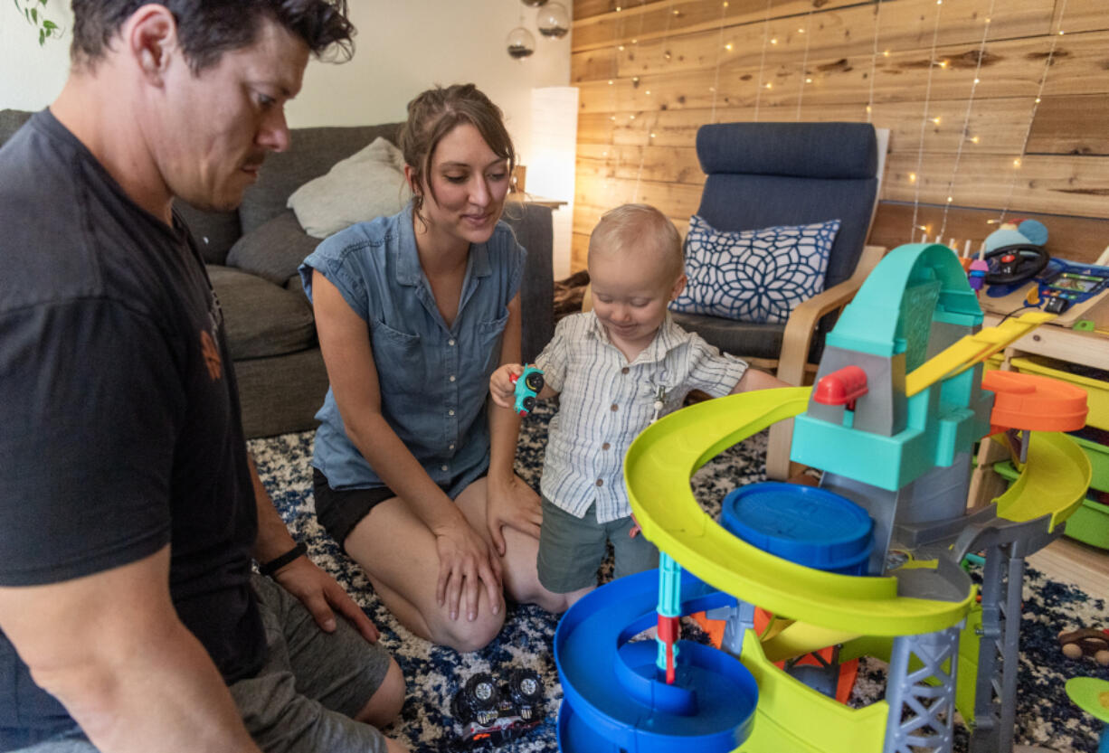 Aynsley, from left, and his wife, Nicci, watch 15-month-old Everett play with a race car set at the Silva residence in Vancouver. The Silvas received an emergency room hospital bill with a $4,178 charge they were not expecting from PeaceHealth while Nicci Silva was pregnant.