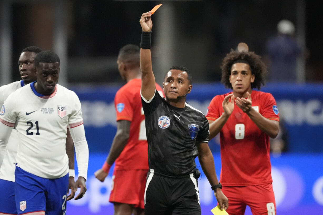 Referee Ivan Barton sends off Tim Weah (21) of the United States, left, during a Copa America Group C soccer match against Panama in Atlanta, Thursday, June 27, 2024.
