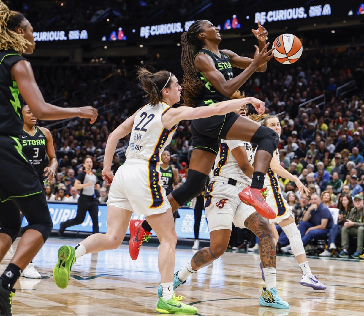 Indiana Fever's Caitlin Clark (22) punches the ball out of the hands of Seattle Storm's Ezi Magbegor during the first half of a WNBA basketball game Thursday, June 27, 2024, in Seattle.