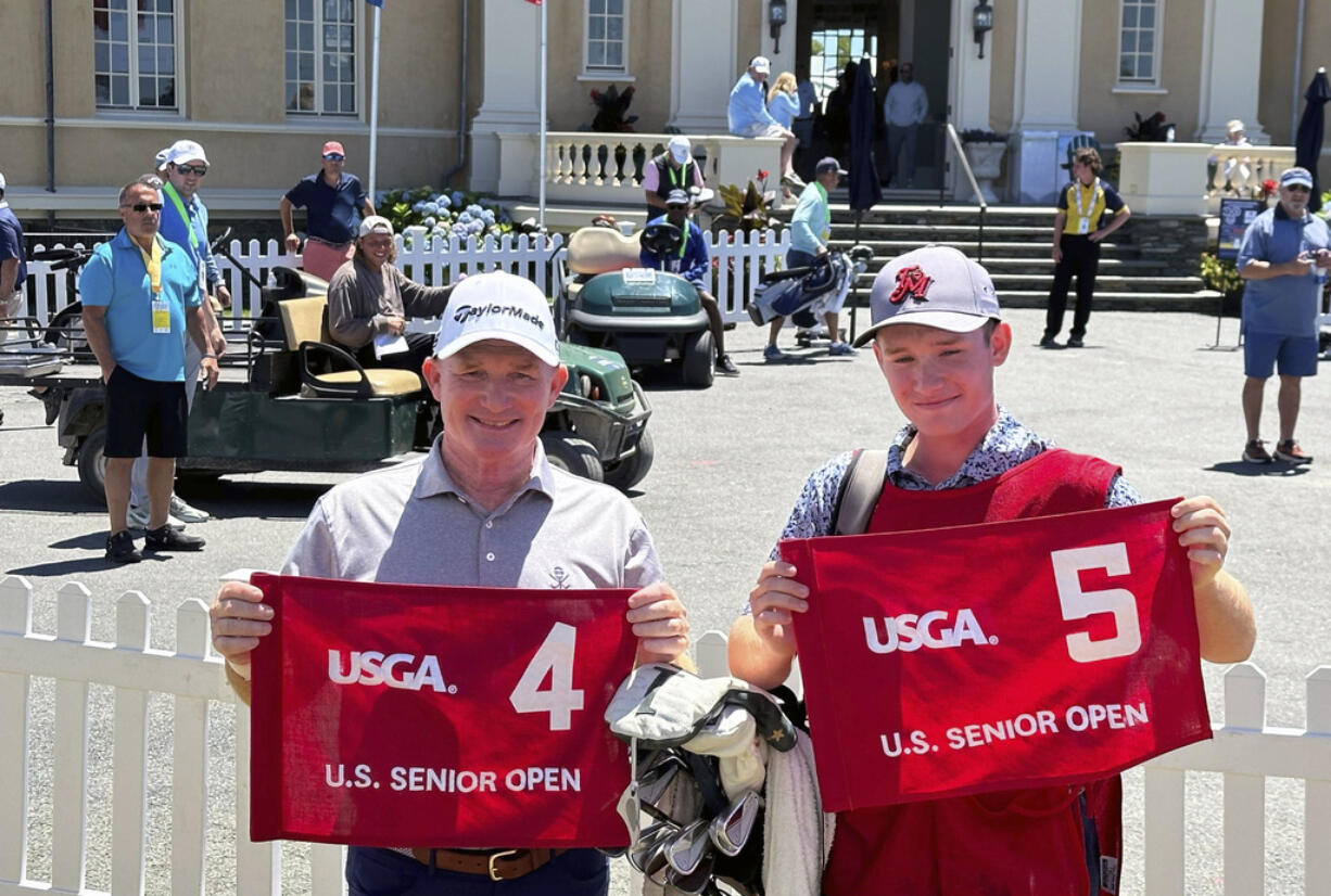 Frank Bensel, left, and his caddie and 14-year-old son, Hagen, pose with hole 4 and 5 flags after Bensel turned up a pair of aces on the back-to-back holes during the second round of the U.S. Senior Open golf tournament in Newport, R.I., Friday, June 28, 2024.