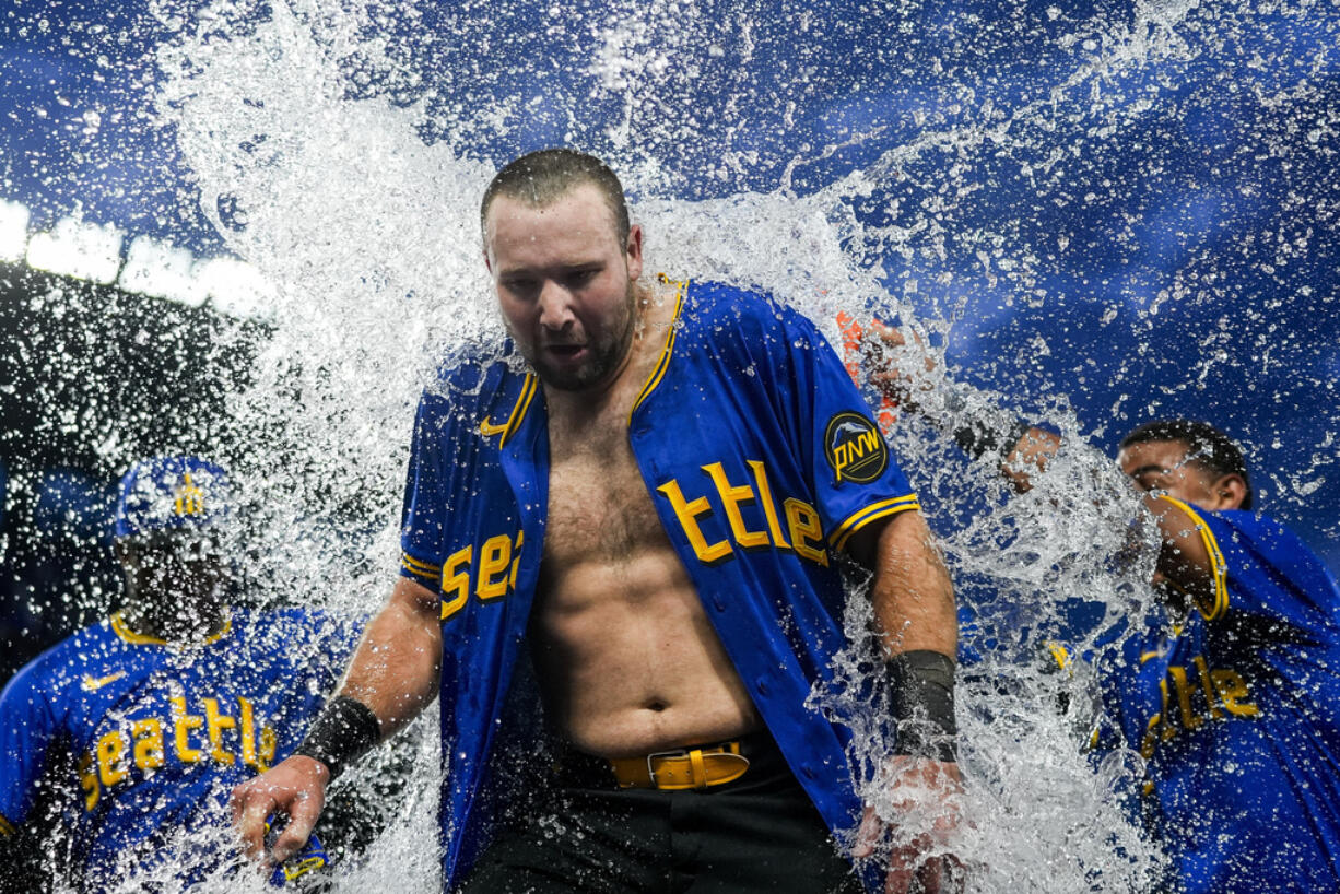 Seattle Mariners' Cal Raleigh is doused by teammates after hitting a ground ball to drive in the winning run in the 10th inning against the Minnesota Twins in a baseball game Friday, June 28, 2024, in Seattle. The Mariners won 3-2.