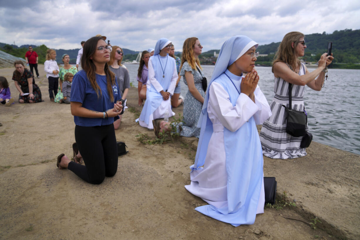 Sister Mary Fatima Pham, second from right, kneels June 23 with her fellow Catholics as they watch the Eucharist brought on board a boat on the Ohio River at the Steubenville Marina in Steubenville, Ohio.