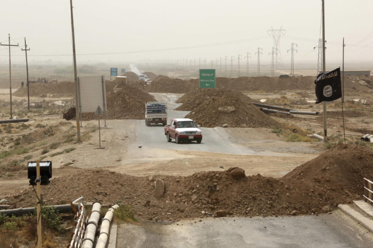 FILE - Islamic State militants passing a checkpoint bearing the group&rsquo;s trademark black flag in the village of Maryam Begg in Kirkuk, 290 kilometers (180 miles) north of Baghdad, Iraq, Sept. 29, 2014. Ten years after the Islamic State group declared its caliphate in large parts of Iraq and Syria, the extremists now control no land, have lost many prominent founding leaders and are mostly away from the world news headlines.