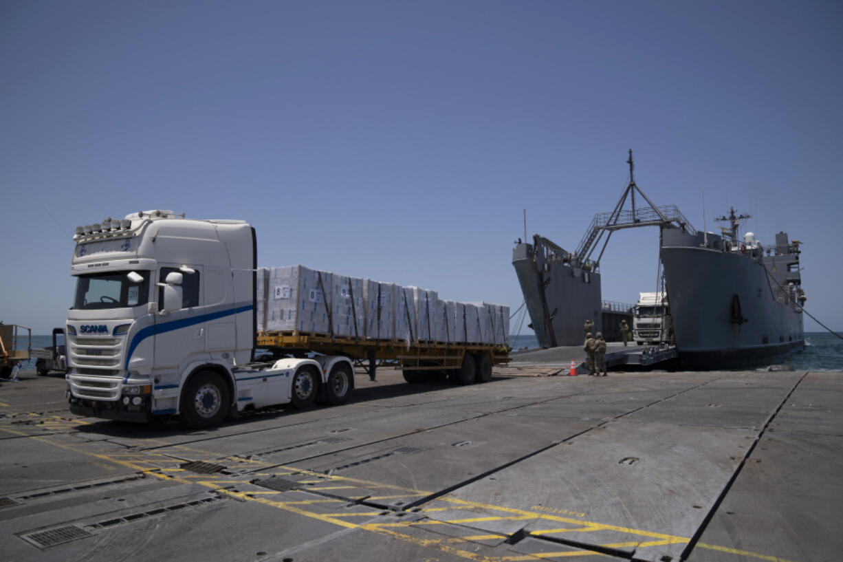 U.S. Army soldiers stand next to trucks arriving loaded with humanitarian aid at the U.S.-built floating pier Trident before reaching the beach on the coast of the Gaza Strip, Tuesday, June 25, 2024.