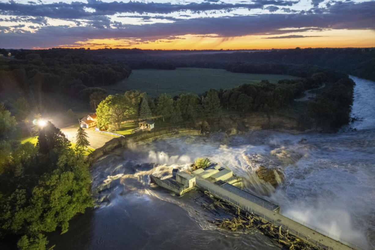 This long-exposure drone photo provided by AW Aerial shows a home as it teeters before partially collapsing into the Blue Earth River at the Rapidan Dam in Rapidan, Minn., Tuesday, June 25, 2024.