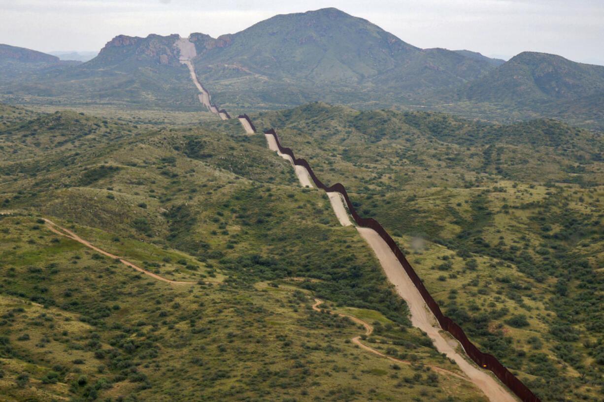 FILE - The border between the United States and Mexico, at right, cuts through the Sonoran Desert at the base of the Baboquivari Mountains, Thursday, Sept. 8, 2022, near Sasabe, Ariz. The bodies of three Mexican migrants have brern found Wednesday, June 27, 2024, in the Sonoran Desert near the Arizona-Mexico border as temperatures hit the triple digits across parts of the Southwest.