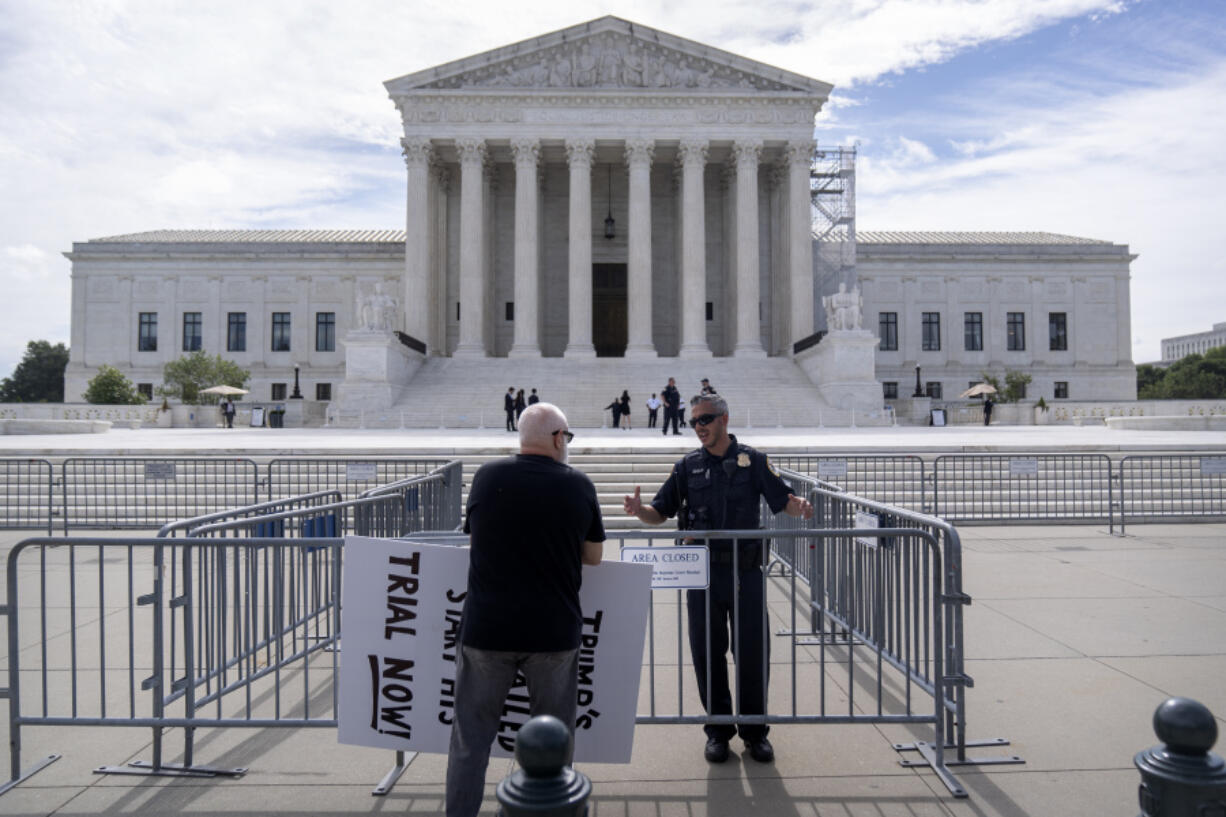 A Supreme Court police officer talks with a demonstrator at a barricade outside the Supreme Court on Thursday, June 27, 2024, in Washington.